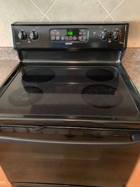 Black electric range with four burners and control panel.