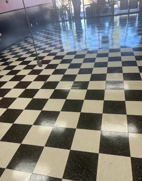 Black and white checkered tile floor in a building, reflecting light and the outside environment.