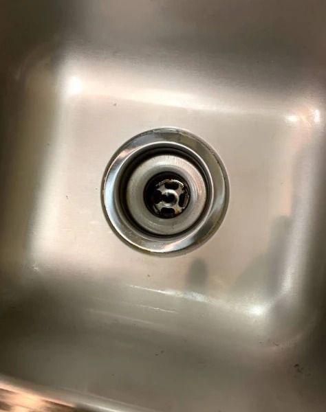 Stainless steel kitchen sink with a drain.