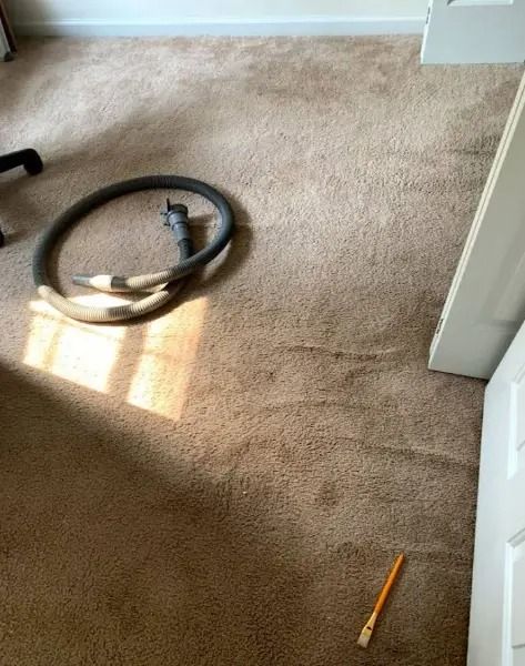 Beige carpet with dark patches, a vacuum hose, and a pencil.