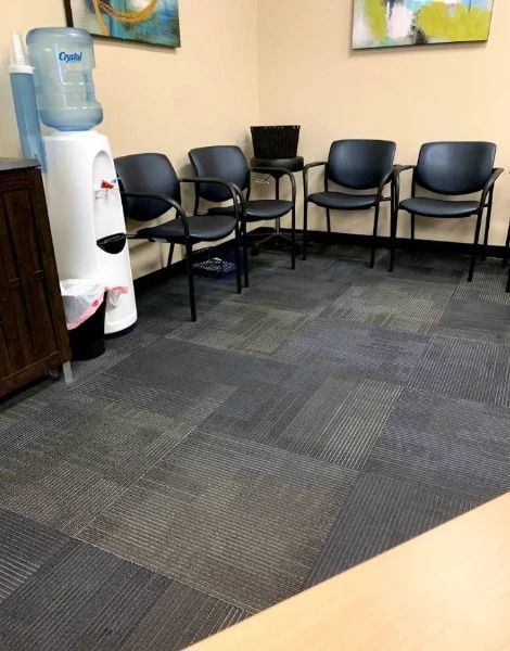 Waiting room with four chairs, a water cooler, and art on the wall.