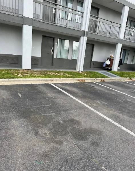 Exterior view of a motel with a parking lot in front.