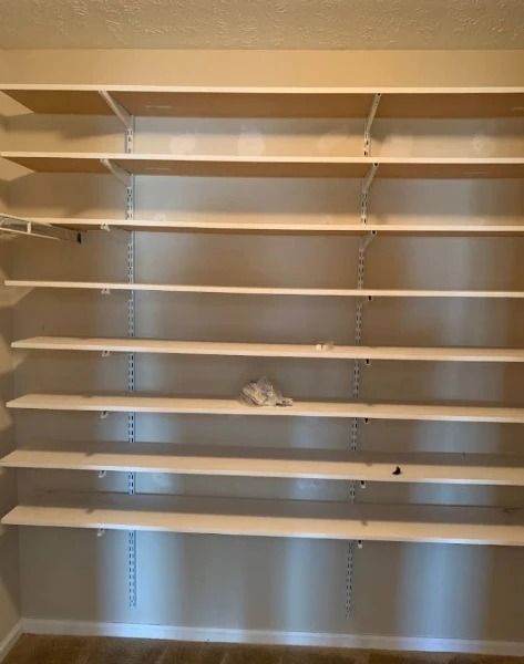 Empty white shelving unit against a beige wall in a room.