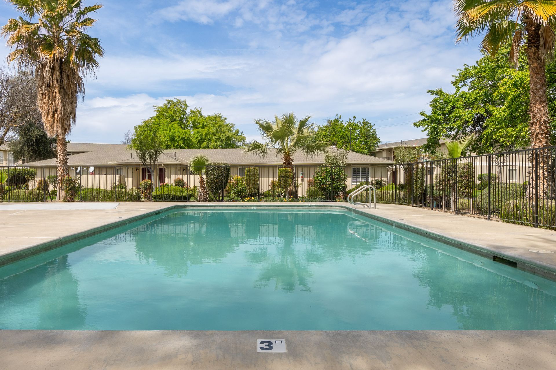 Swimming pool with apartment buildings in the background under a blue sky.