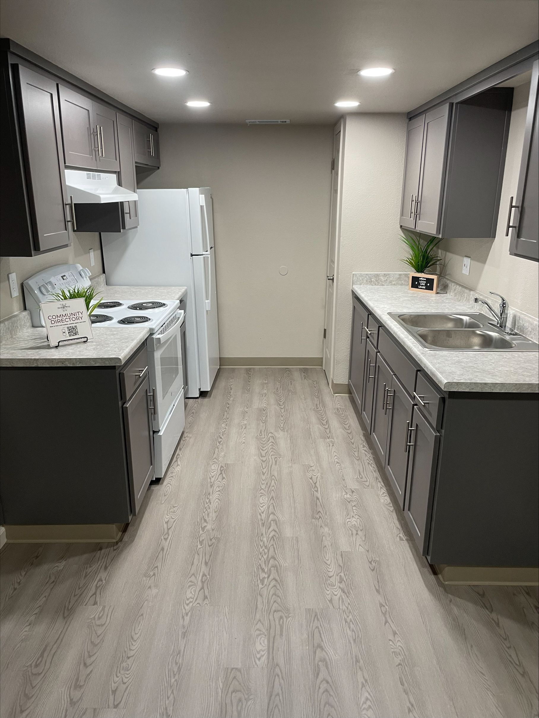 Gray kitchen with white appliances and countertops. Light wood-look flooring.