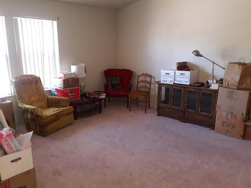 Living room with furniture, boxes, and a window with vertical blinds.