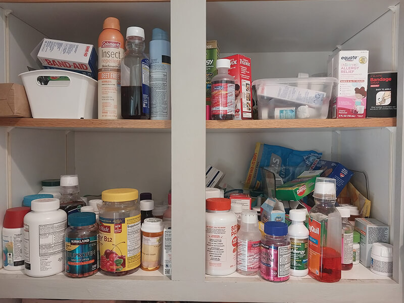 Medicine cabinet filled with various bottles, containers, and products on shelves.