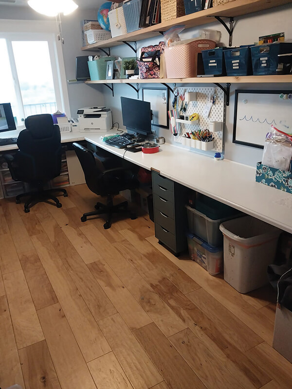Office space with two desks, shelves, and wood floors.