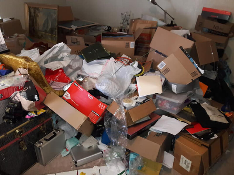 Cluttered room with overflowing boxes, papers, and miscellaneous items; a storage space in disarray.
