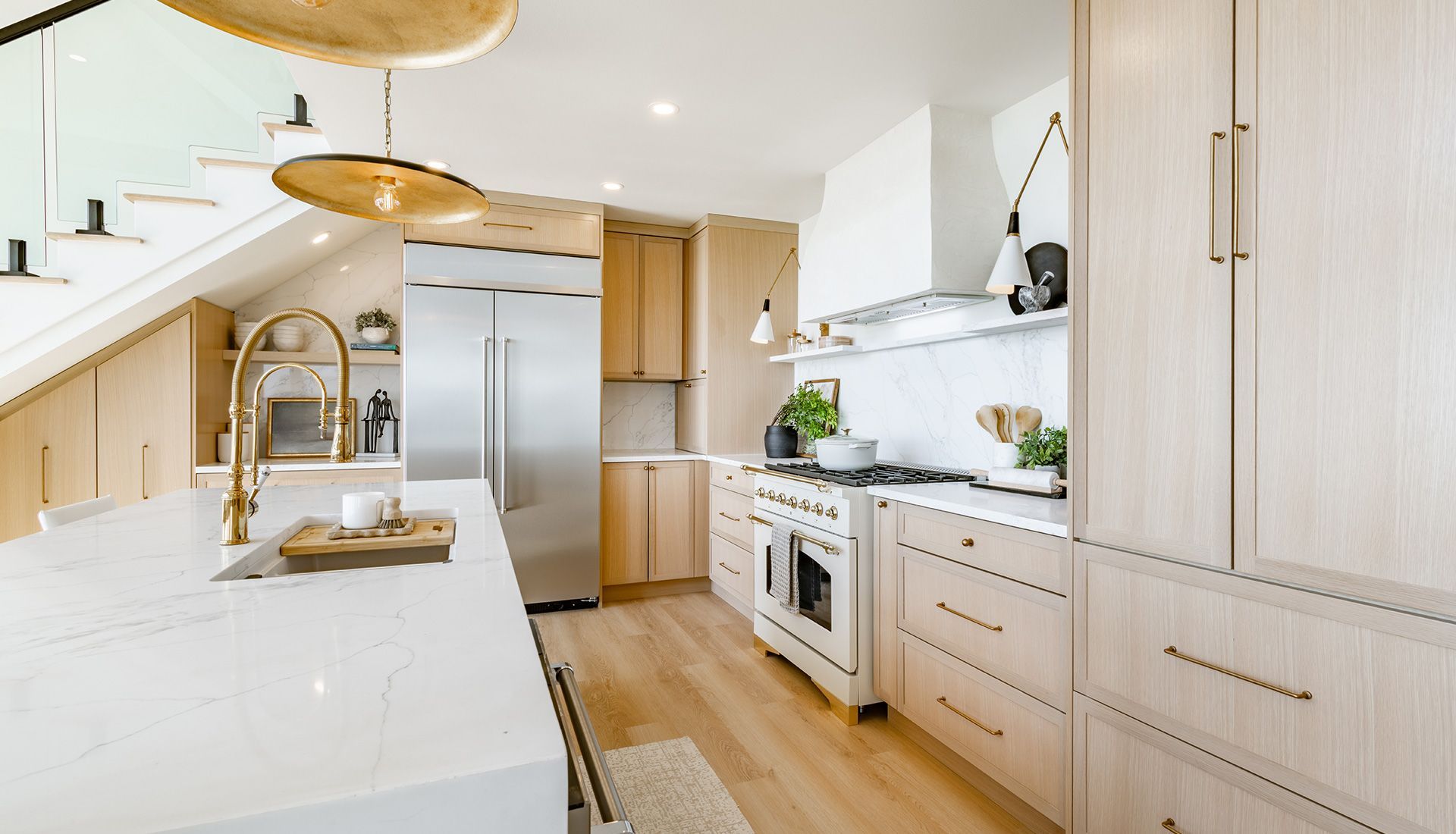 Modern kitchen with light wood cabinets, stainless steel appliances, and white countertops.
