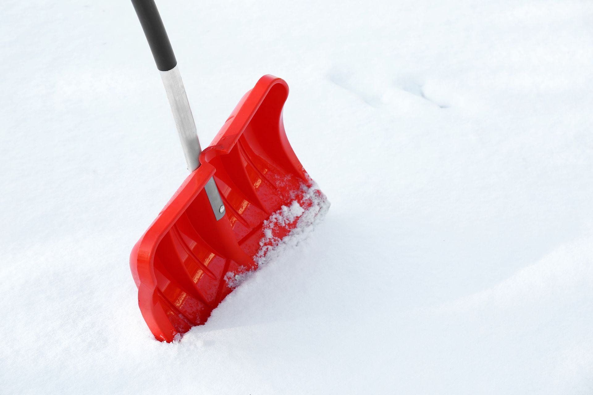 Red snow shovel pushing through fresh white snow