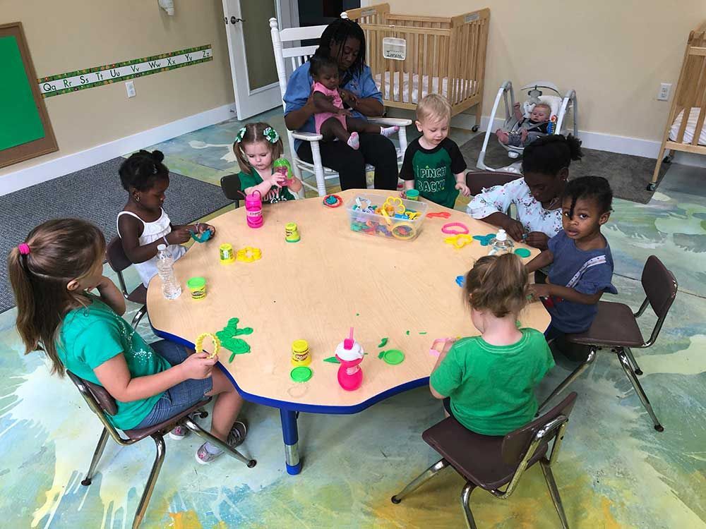 A group of children are sitting on the floor in a classroom.