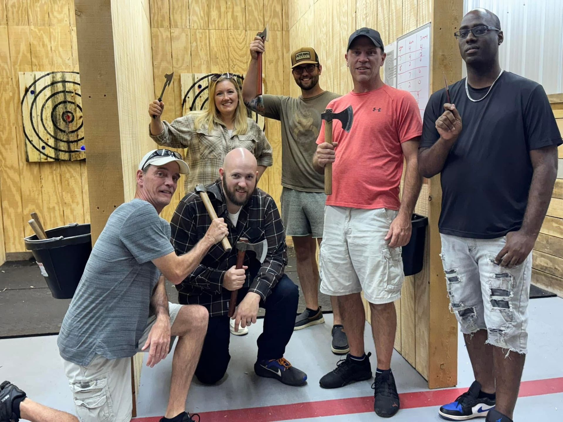 A group of people are posing for a picture while holding axes in a room.