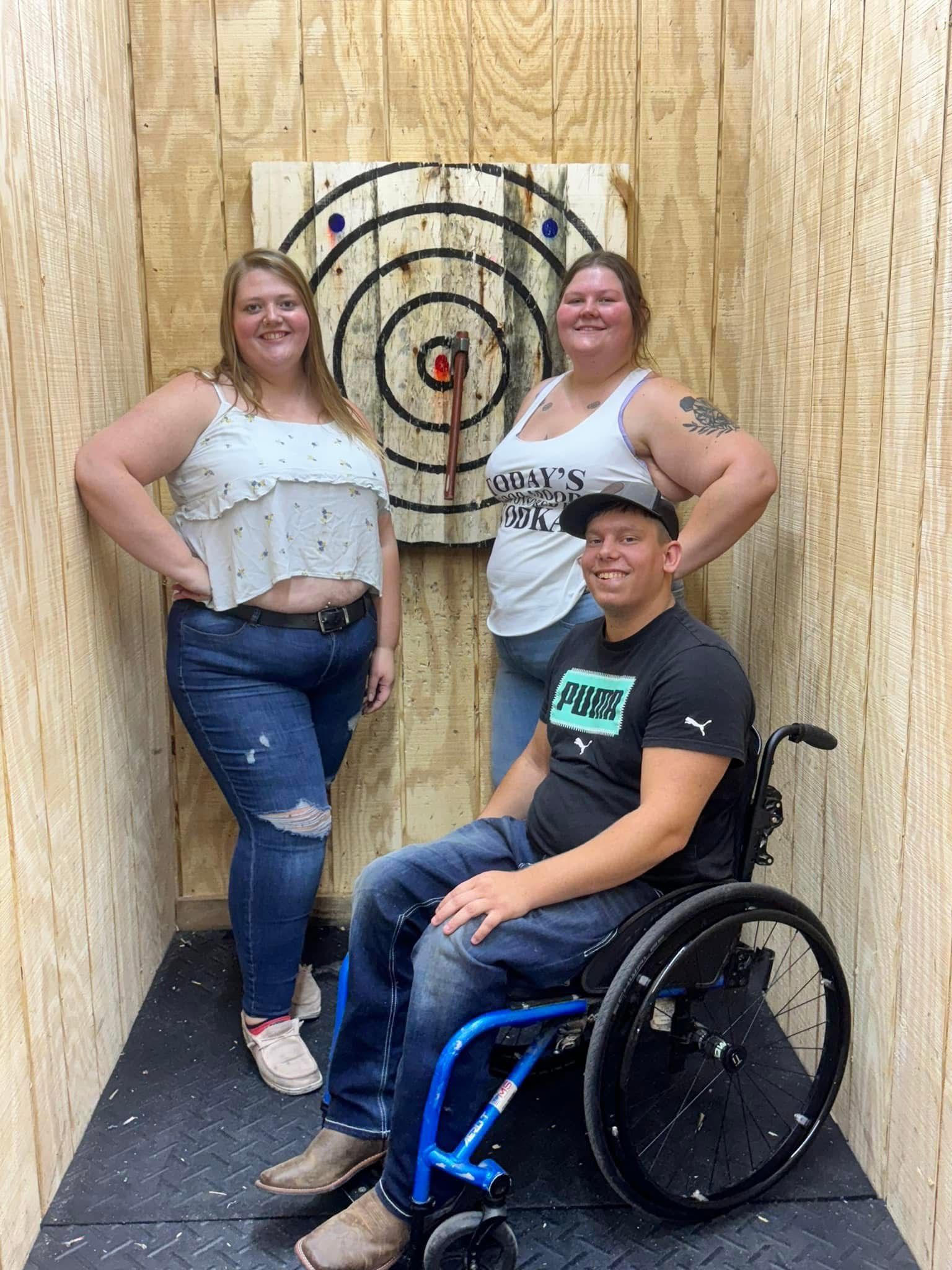 A man in a wheelchair is standing next to two women.