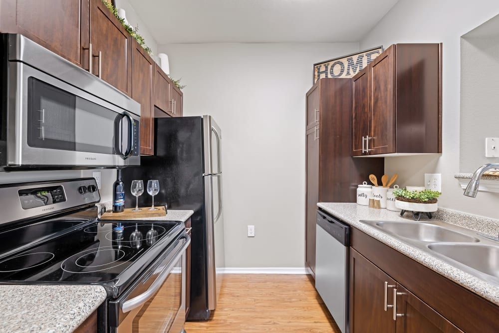 a kitchen with stainless steel appliances and wooden cabinets at Marquis on Gaston in Dallas, TX.