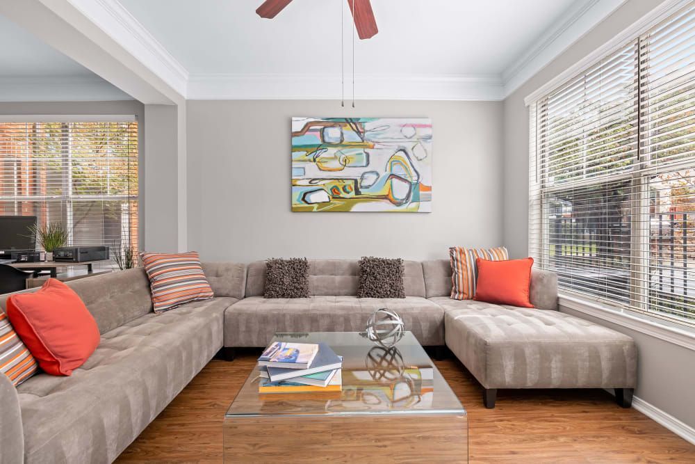 a living room with a large sectional couch, a coffee table, and a ceiling fan at Marquis on Gaston in Dallas, TX.