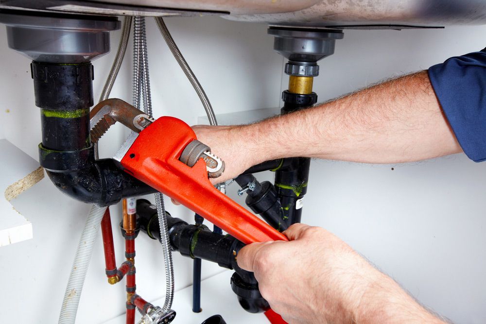 Skilled plumber using a wrench to repair a black pipe — Advanced Flow Plumbing In Innes Park QLD