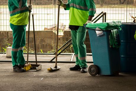 Deux hommes se tiennent l'un à côté de l'autre, tenant une serpillière et un balai.