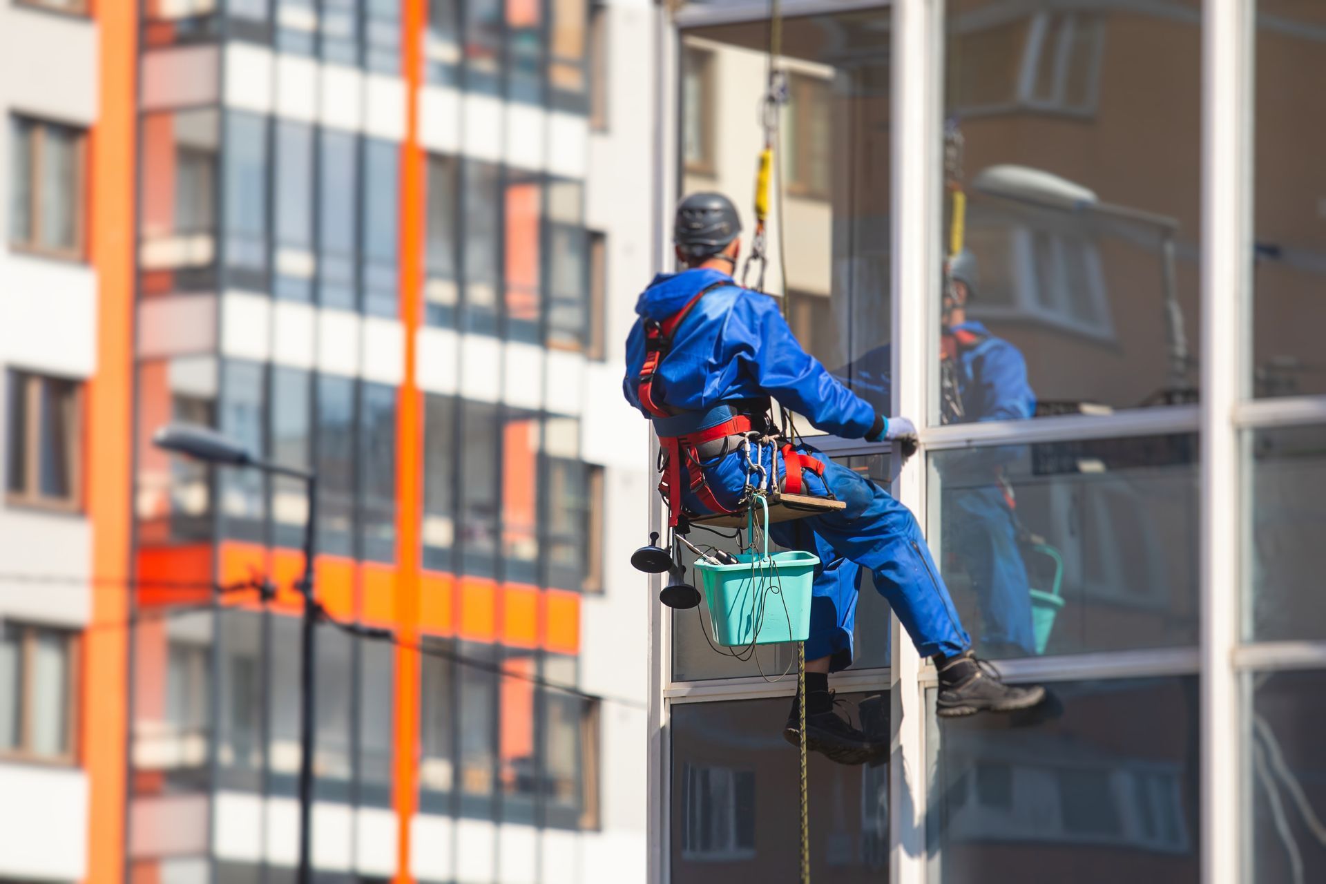 Un homme nettoie les fenêtres d'un grand immeuble.