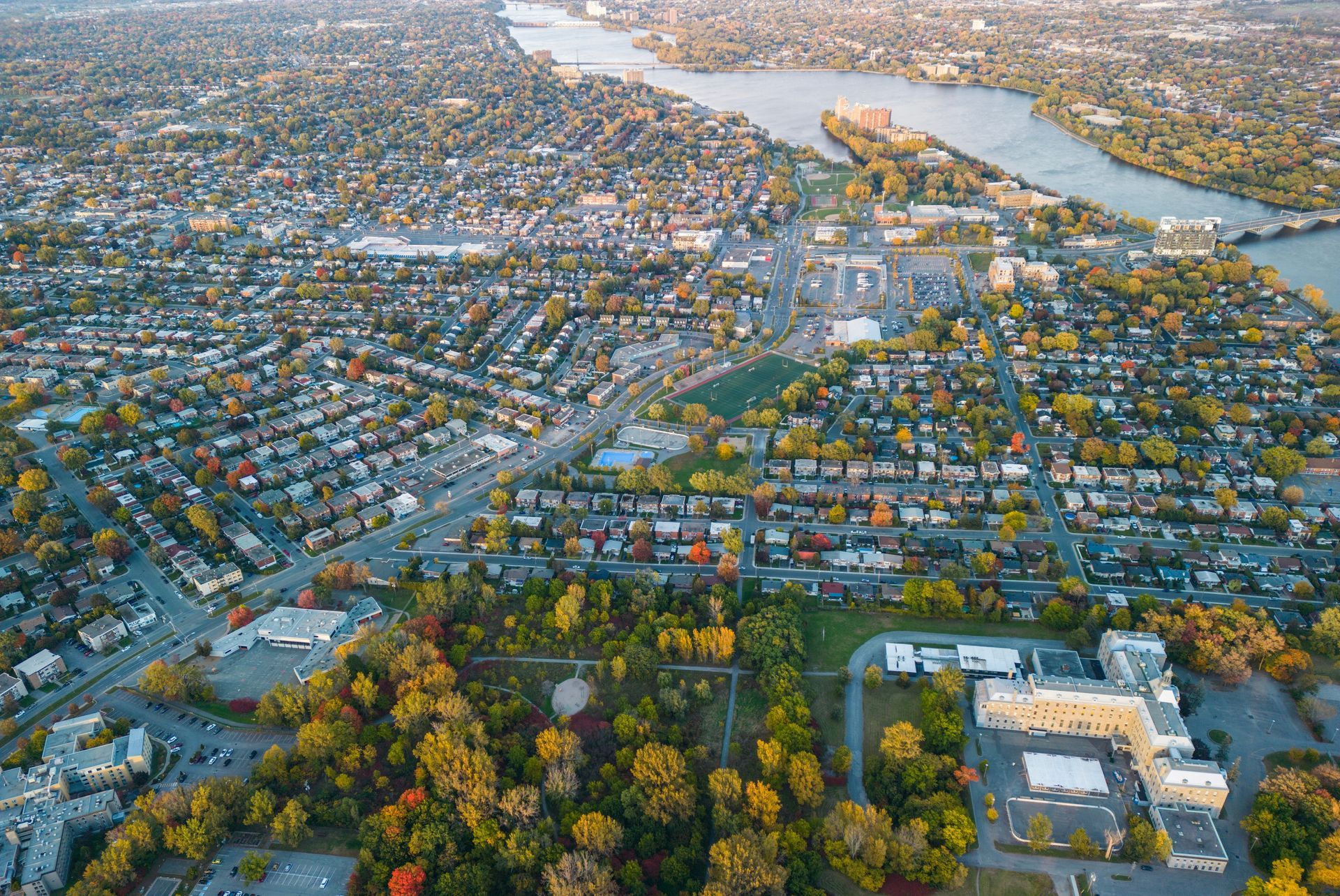 Une vue aérienne d'une ville entourée d'arbres et d'une rivière.