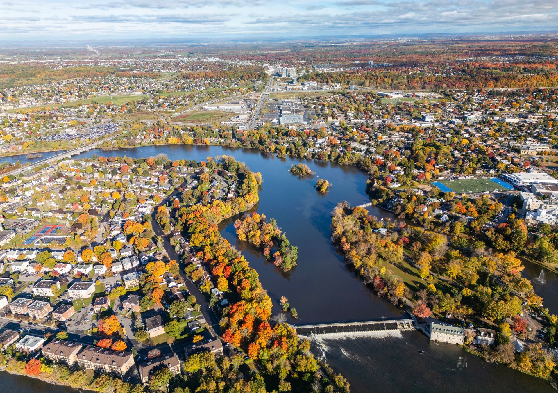 Une vue aérienne d'une rivière entourée d'arbres et d'une ville.