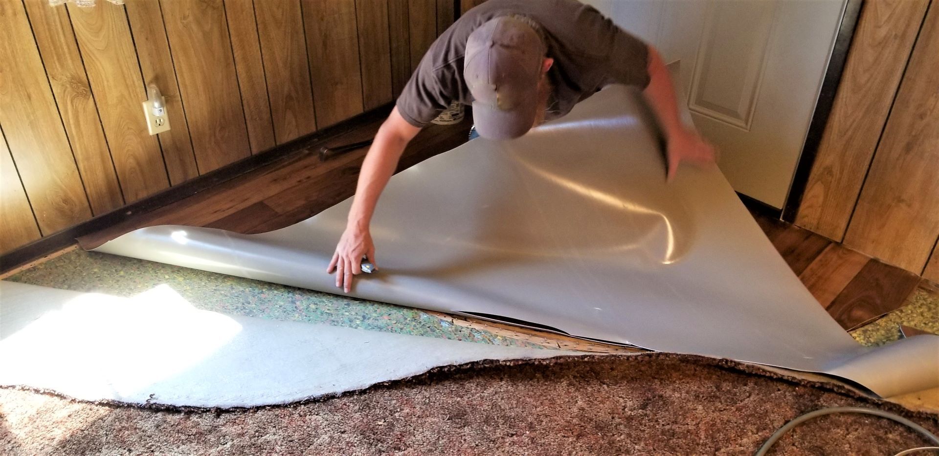 A man is laying carpet on the floor in a room.