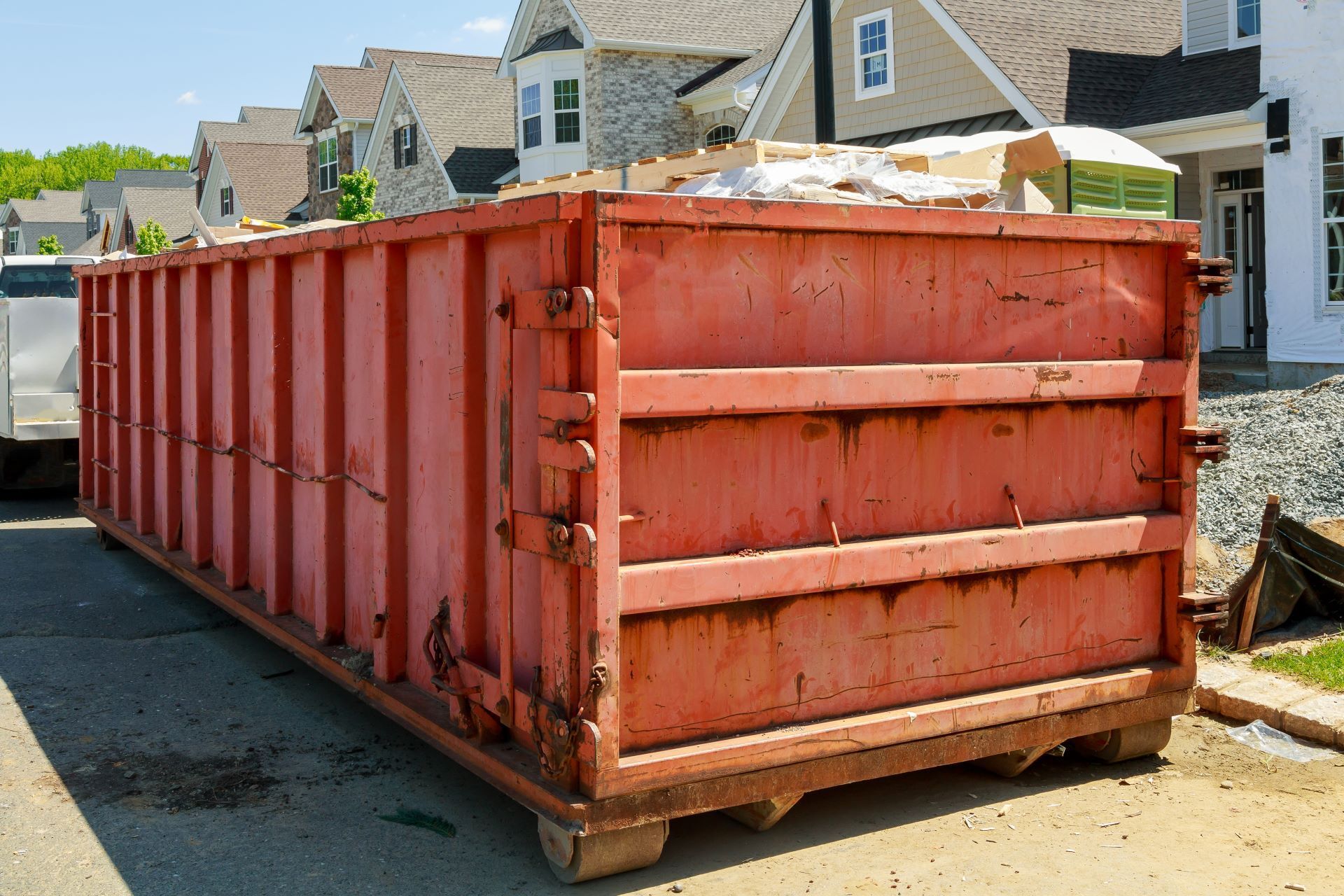 A large red dumpster is parked in front of a house.