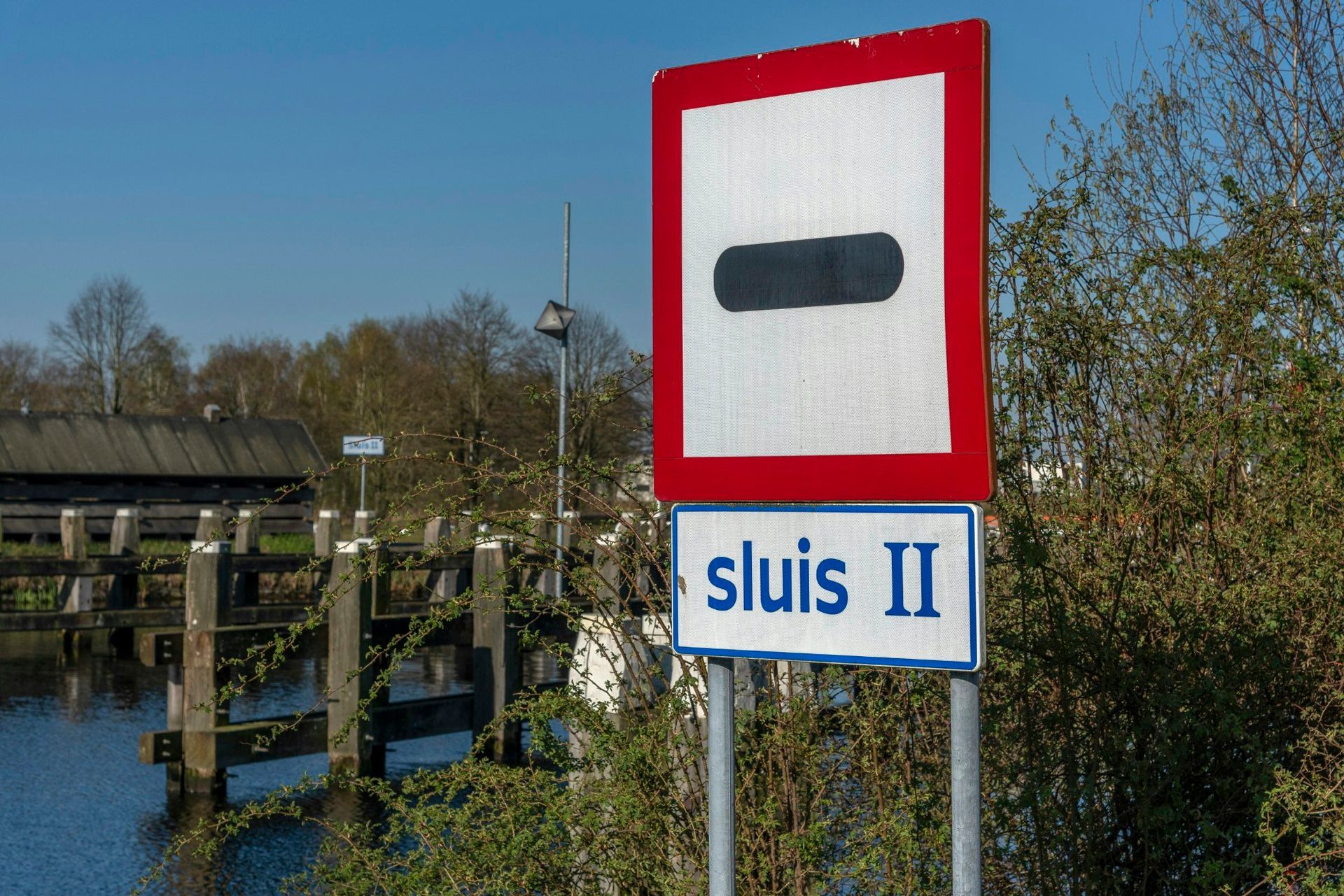 Bordje voor Sluis II met een zwarte rechthoek op een witte achtergrond met een rode rand; blauw bordje met de tekst 