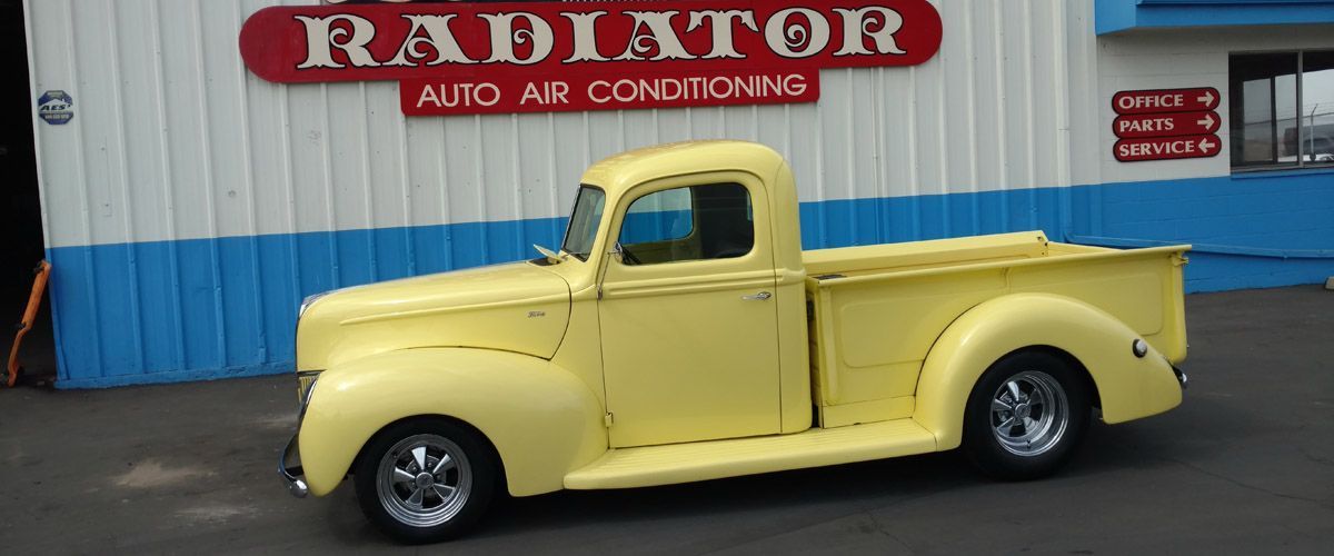 A yellow truck is parked in front of a radiator auto air conditioning shop - Kirk's Radiator & Auto A/C Inc.