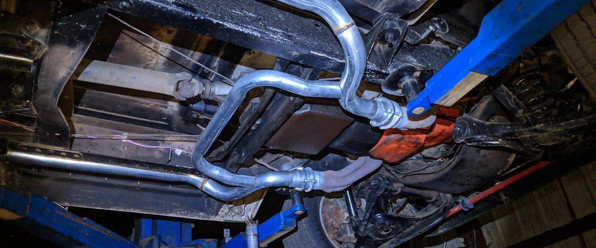 A close up of the underside of a car on a lift - Kirk's Radiator & Auto A/C Inc.