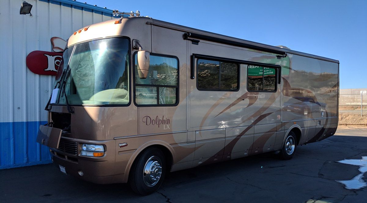 A large brown rv is parked in front of a building - Kirk's Radiator & Auto A/C Inc.