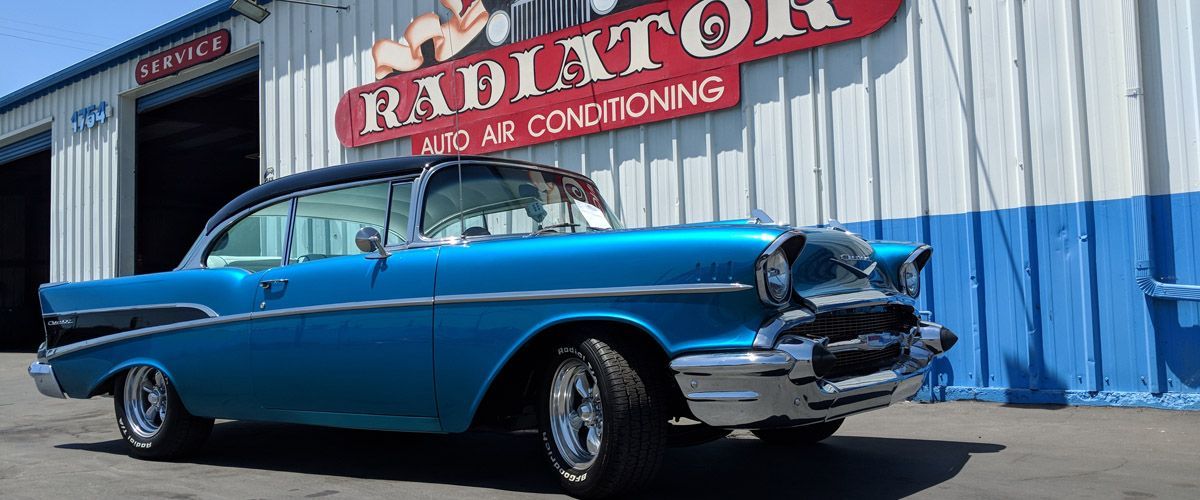 A blue car is parked in front of a radiator shop - Kirk's Radiator & Auto A/C Inc.