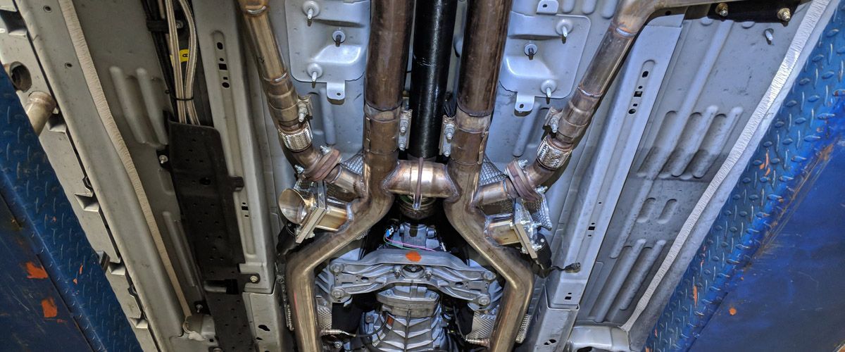 A close up of the underside of a car with exhaust pipes.