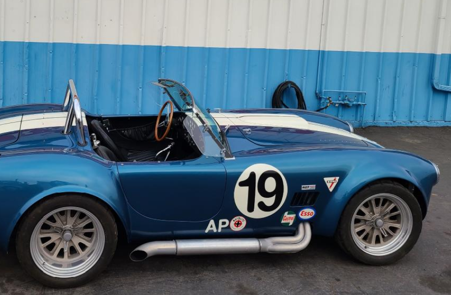 A blue and white sports car with the number 19 on the side is parked in front of a blue and white building.