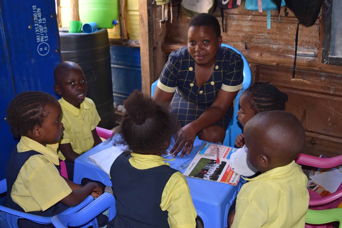 A group of children are sitting around a table with a woman.