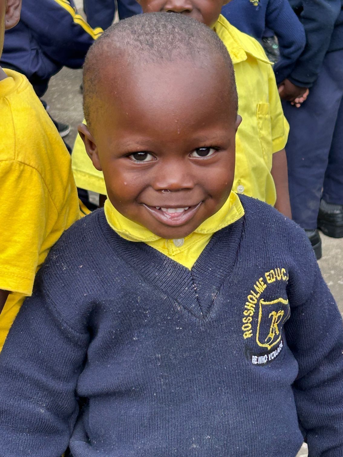 A young boy wearing a blue sweater with the word rossonville on it
