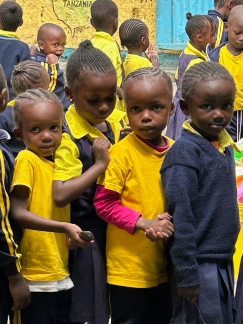 A group of children wearing yellow shirts are shaking hands