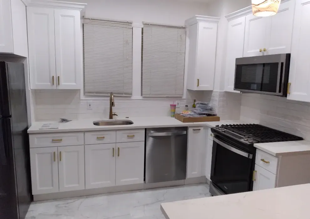 White kitchen with white cabinets, stainless steel appliances, and white countertops.