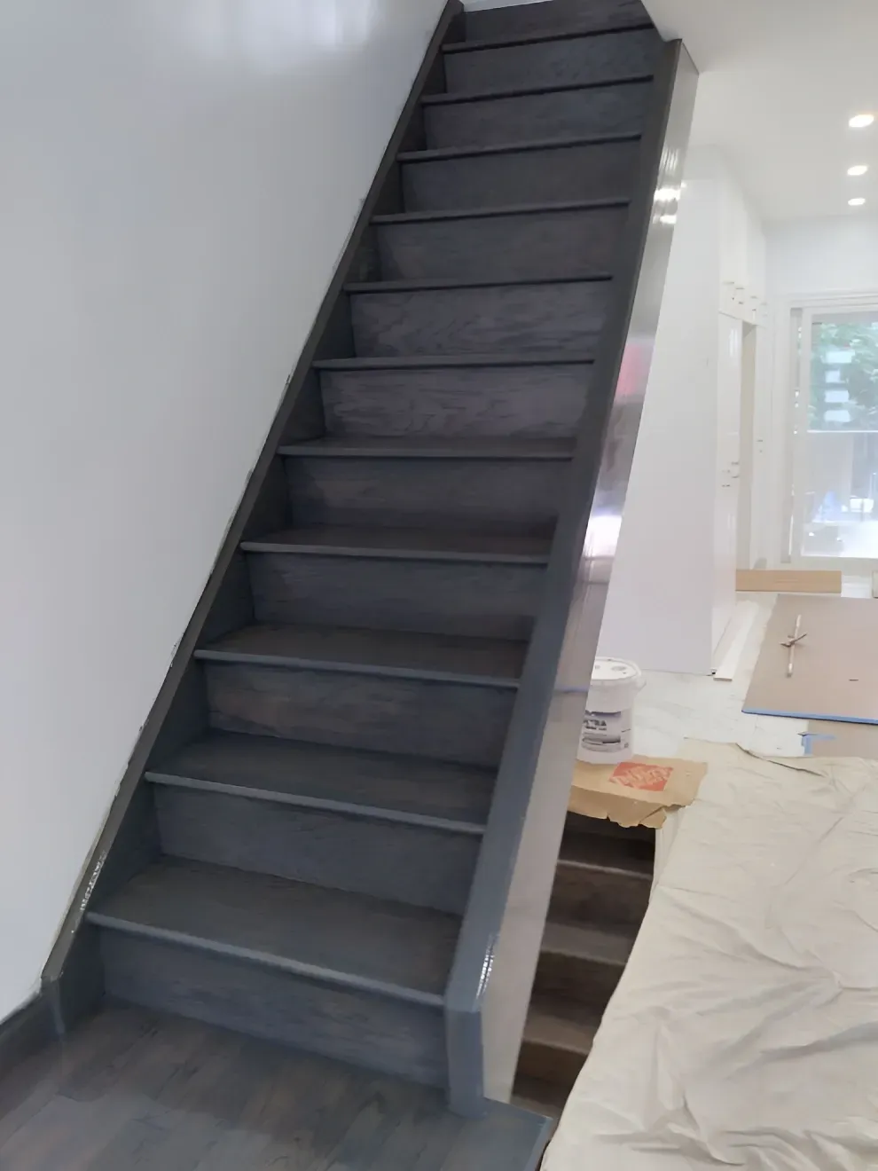 Gray wooden staircase against a white wall; ascending to an unseen area.
