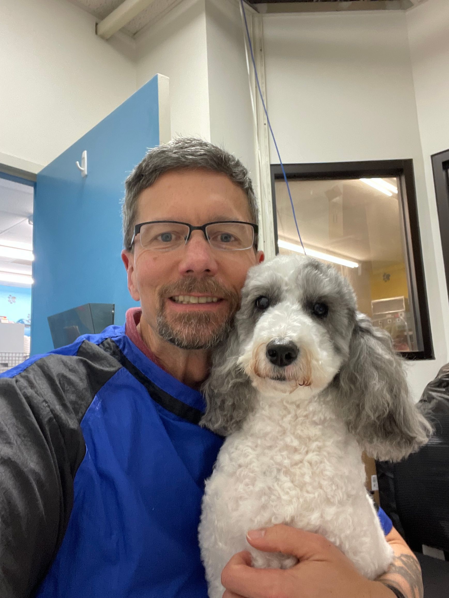 A man is holding a small white dog in his arms.