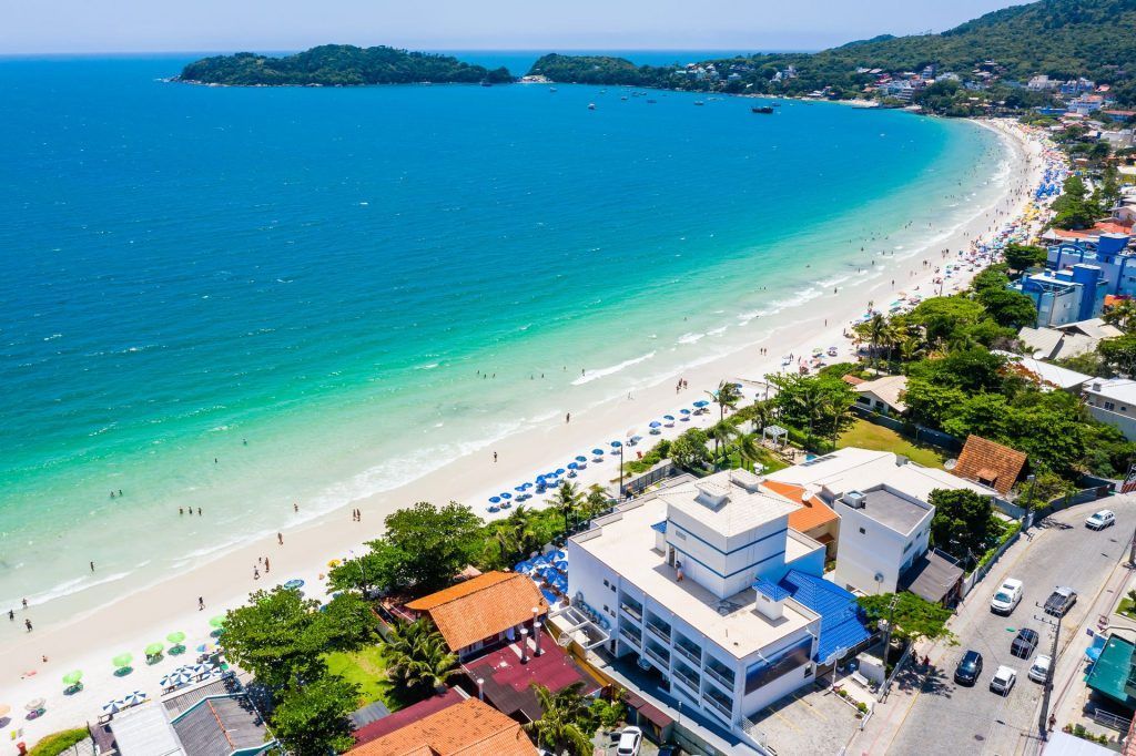 Uma vista aérea de uma praia com um prédio em primeiro plano.