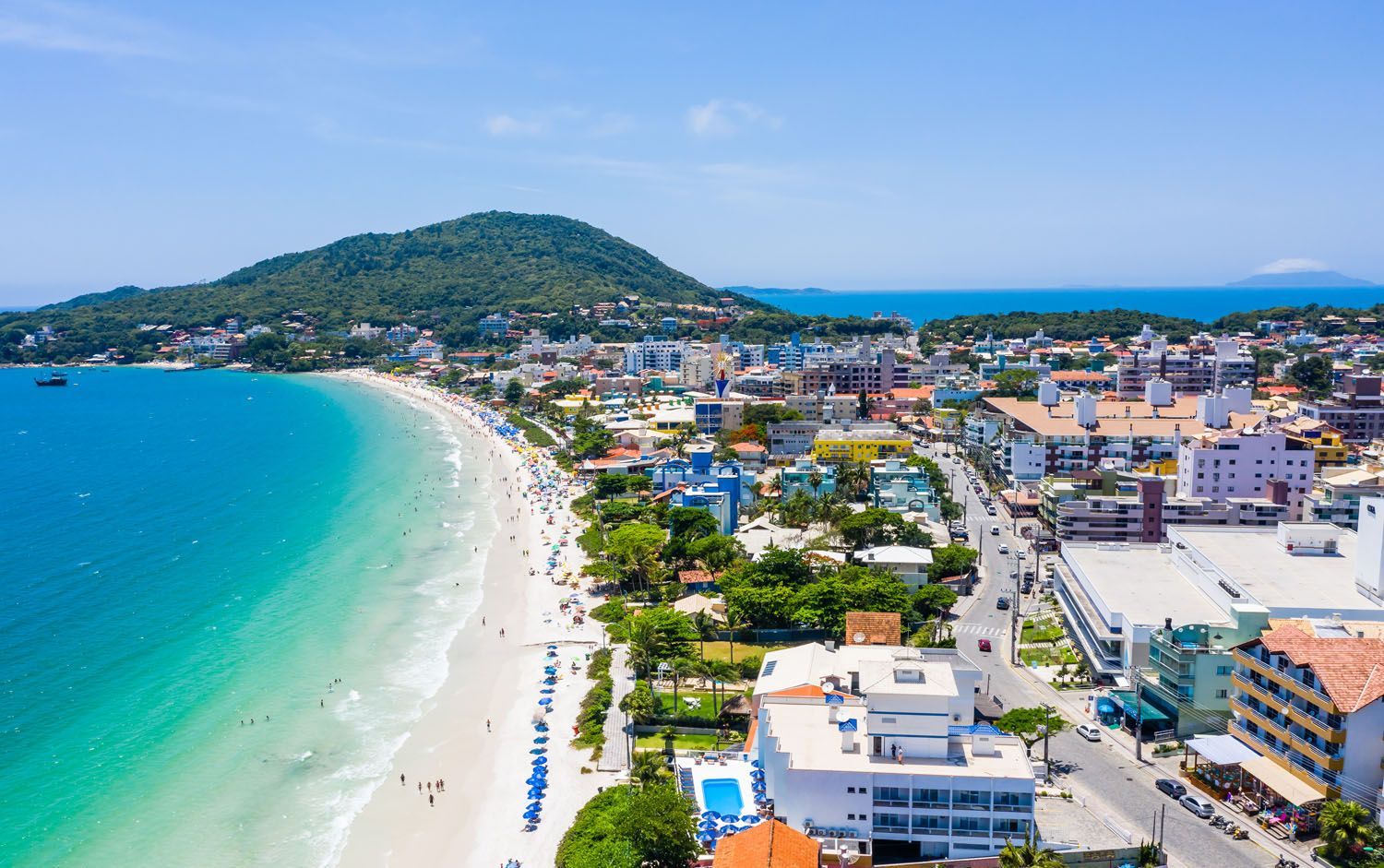 Uma vista aérea de uma praia com uma cidade ao fundo.