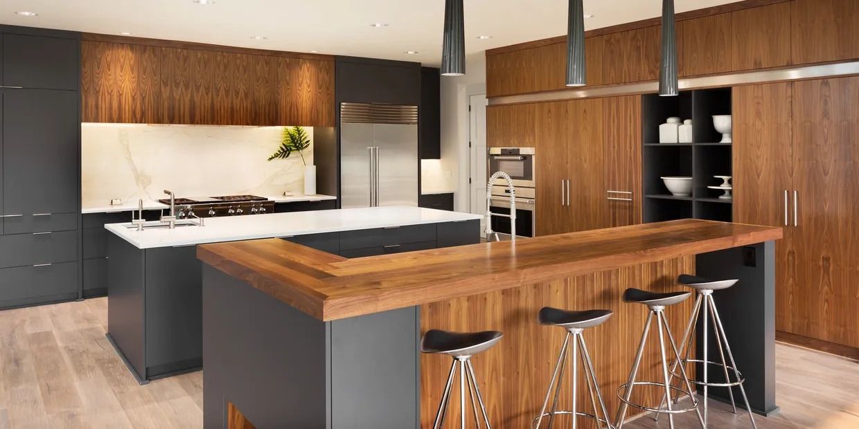 A Kitchen With a Long Wooden Island and Stools — Byron Bay Carpentry and Construction In Suffolk Park, NSW