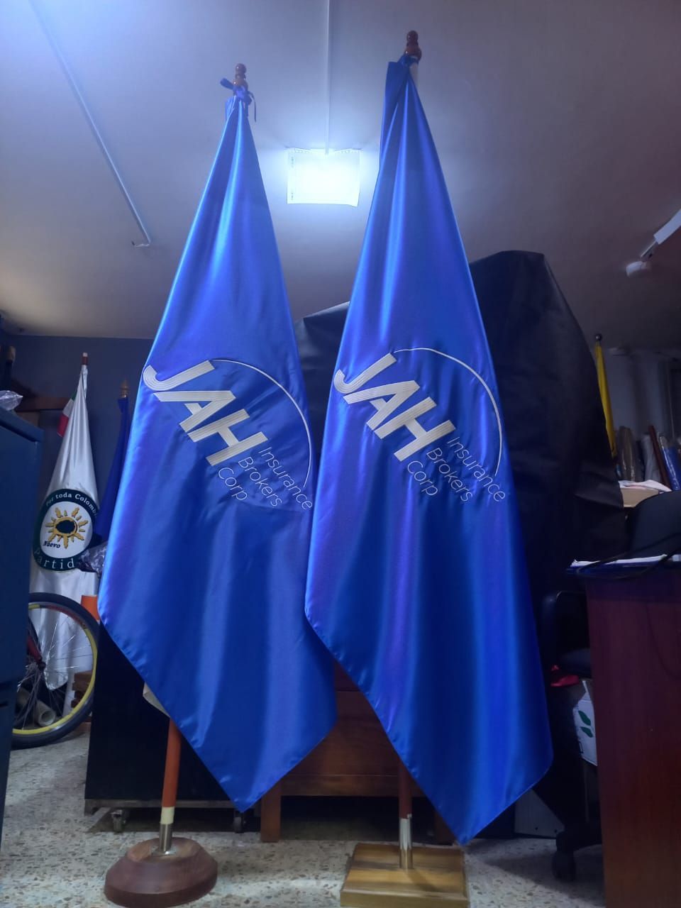 Dos banderas azules de la Fuerza Aérea Japonesa en mástiles en el interior, con una luz brillante encima.