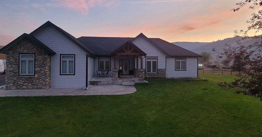 A house with stone accents on the exterior and a porch at sunset. Green lawn in the foreground.