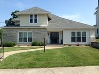 A wooden walkway leading to a gazebo overlooking a body of water at sunset.