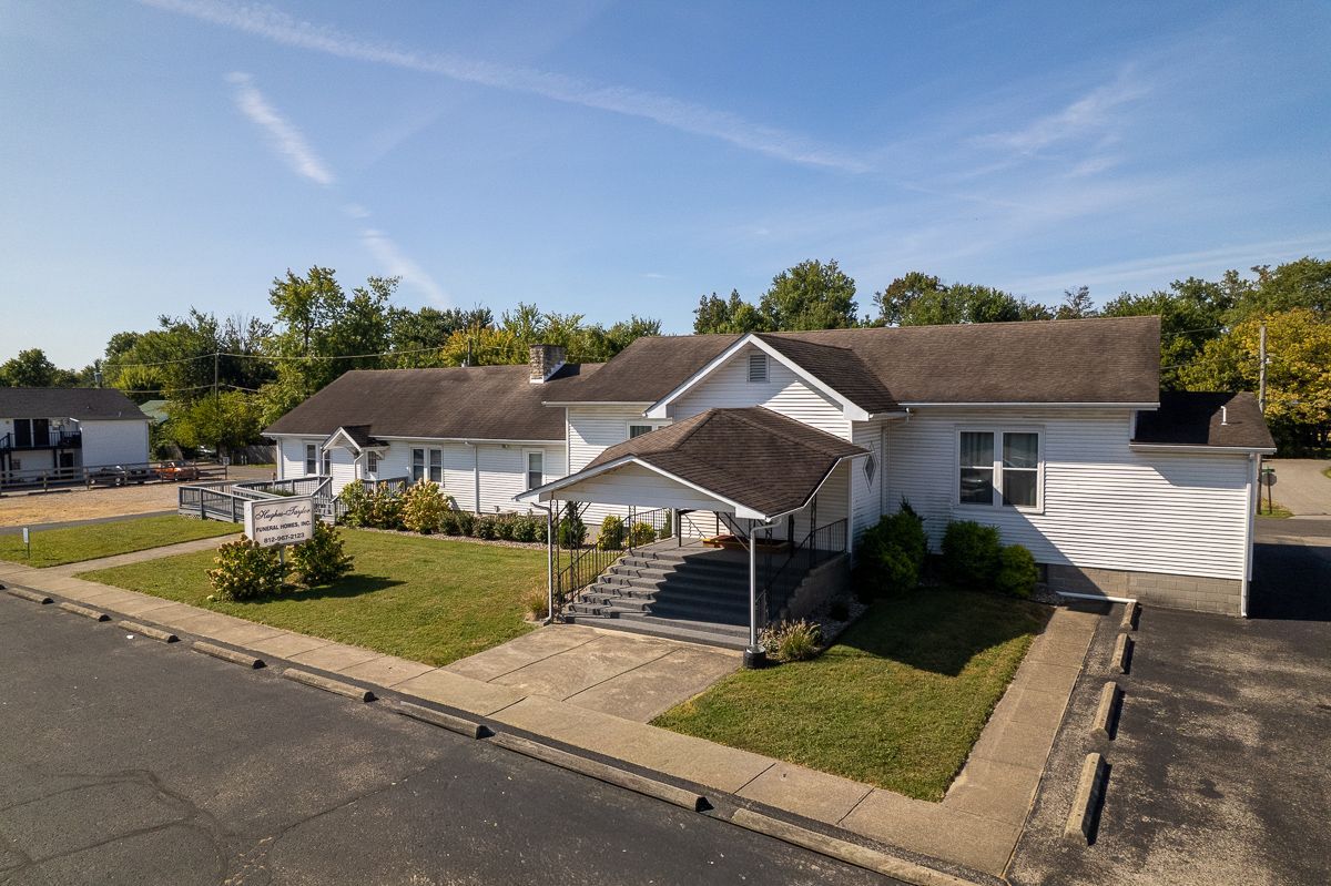 A wooden walkway leading to a gazebo overlooking a body of water at sunset.