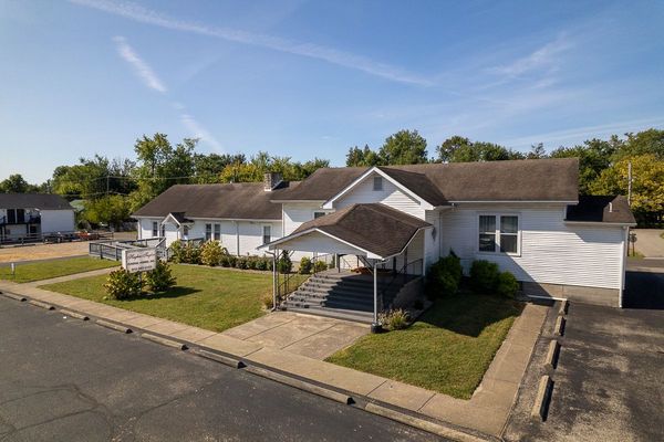 A wooden walkway leading to a gazebo overlooking a body of water at sunset.