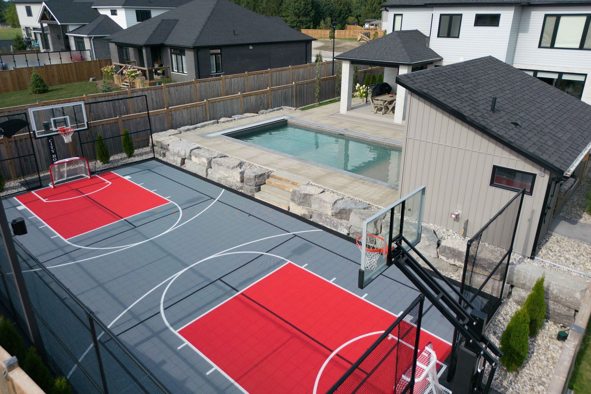 Backyard with two red basketball courts beside a house and swimming pool