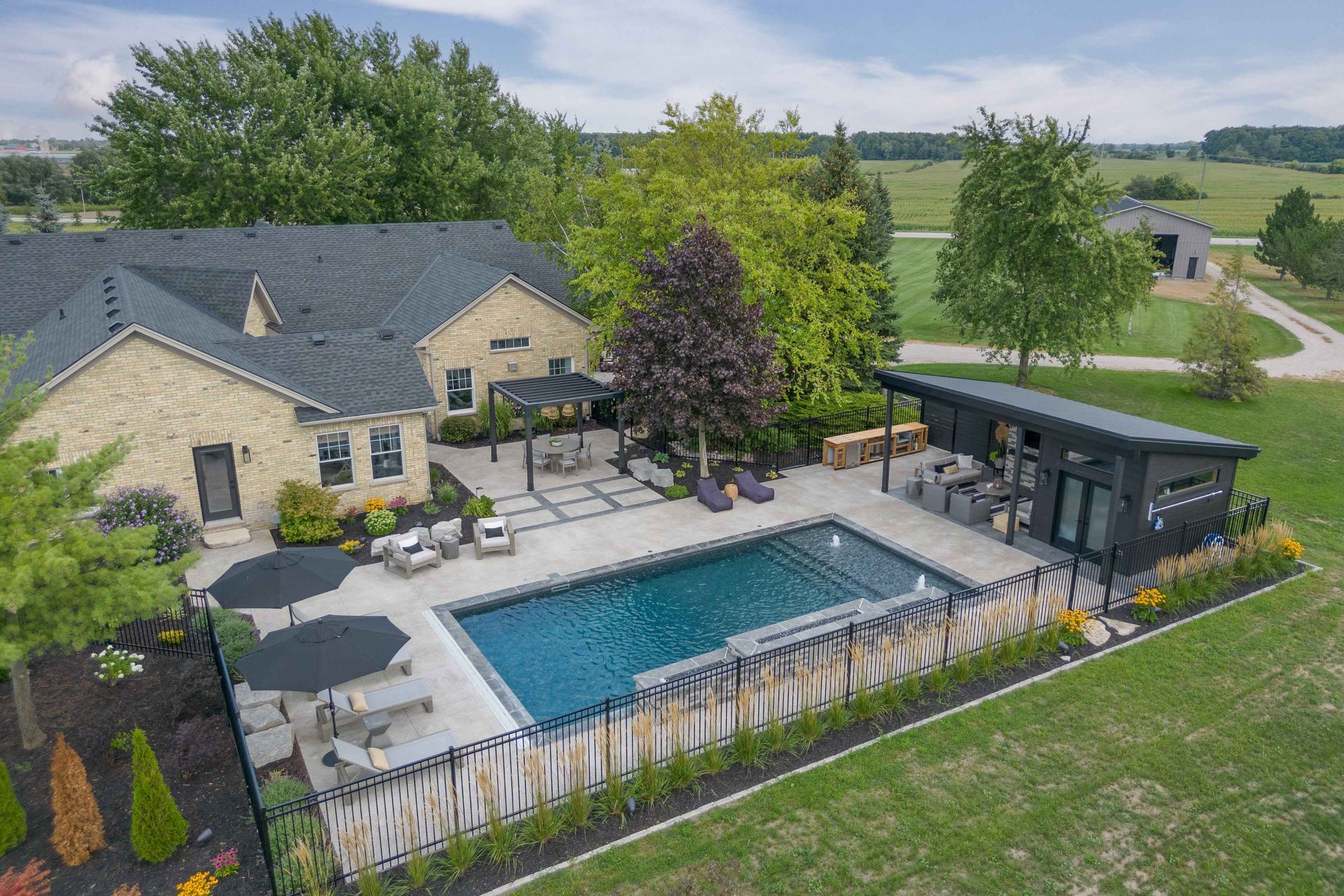 Aerial view of a stone house with a backyard pool, patio, and landscaped yard.
